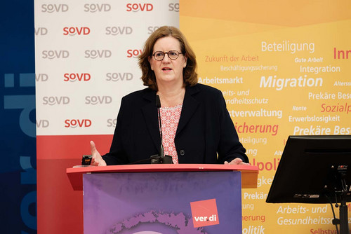 Frau spricht am Rednerpult in ein Mikrofon. 