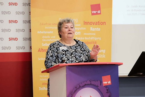 Frau spricht am Rednerpult in ein Mikrofon. 