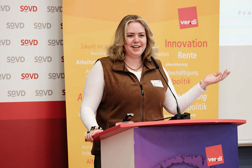 Frau spricht am Rednerpult in ein Mikrofon. 