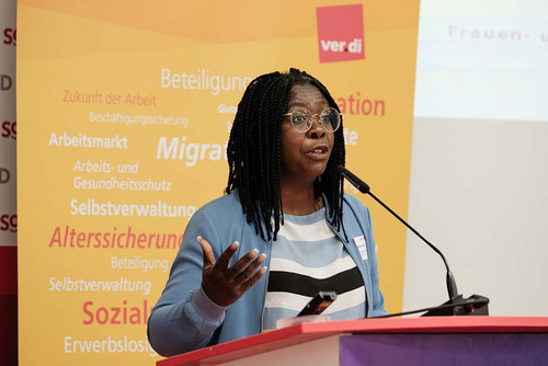 Frau spricht am Rednerpult in ein Mikrofon. 