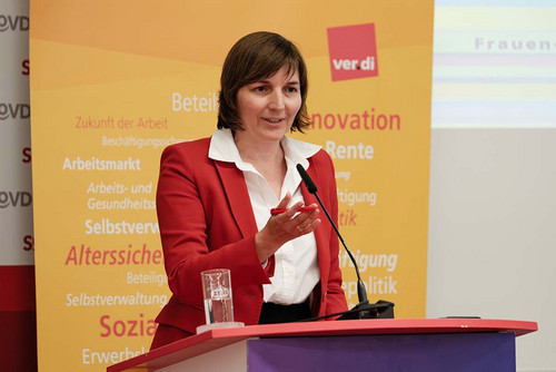 Frau spricht am Rednerpult in ein Mikrofon. 