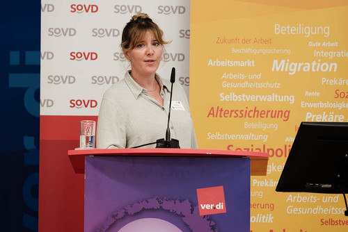 Frau spricht am Rednerpult in ein Mikrofon. 