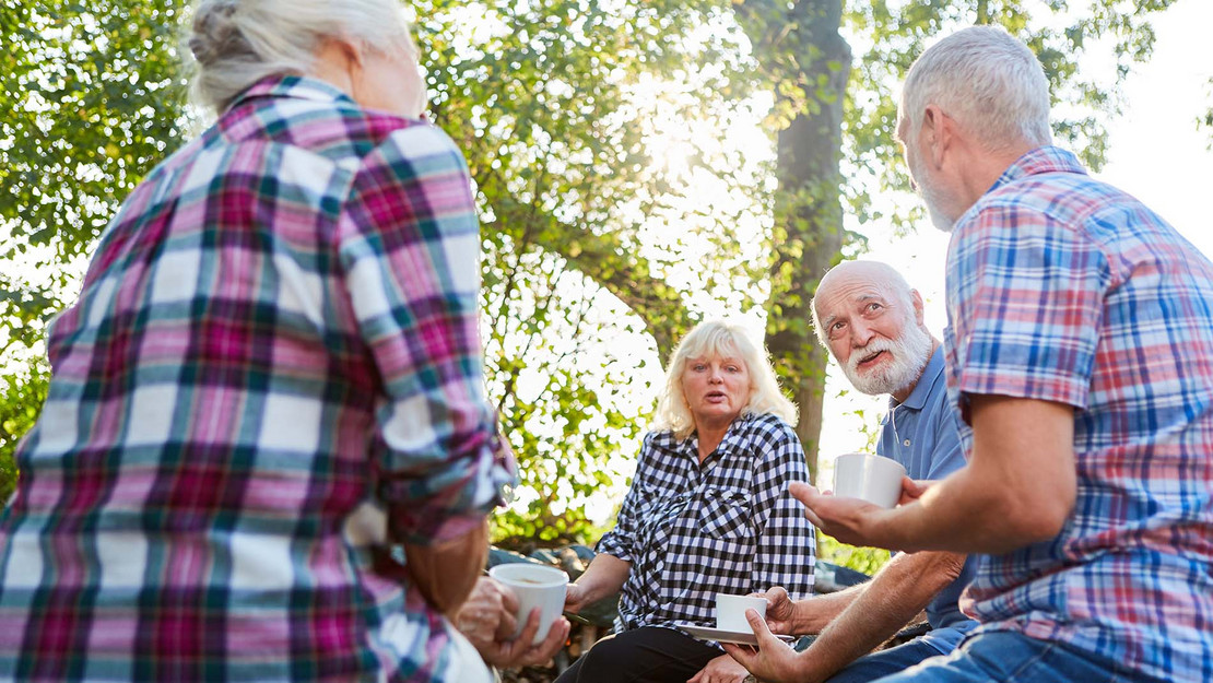 Gruppe von Rentnern sitzt draußen und unterhält sich.
