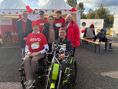 Gruppenbild mit sieben Personen, die beiden vorderen sitzen im Rollstuhl. 