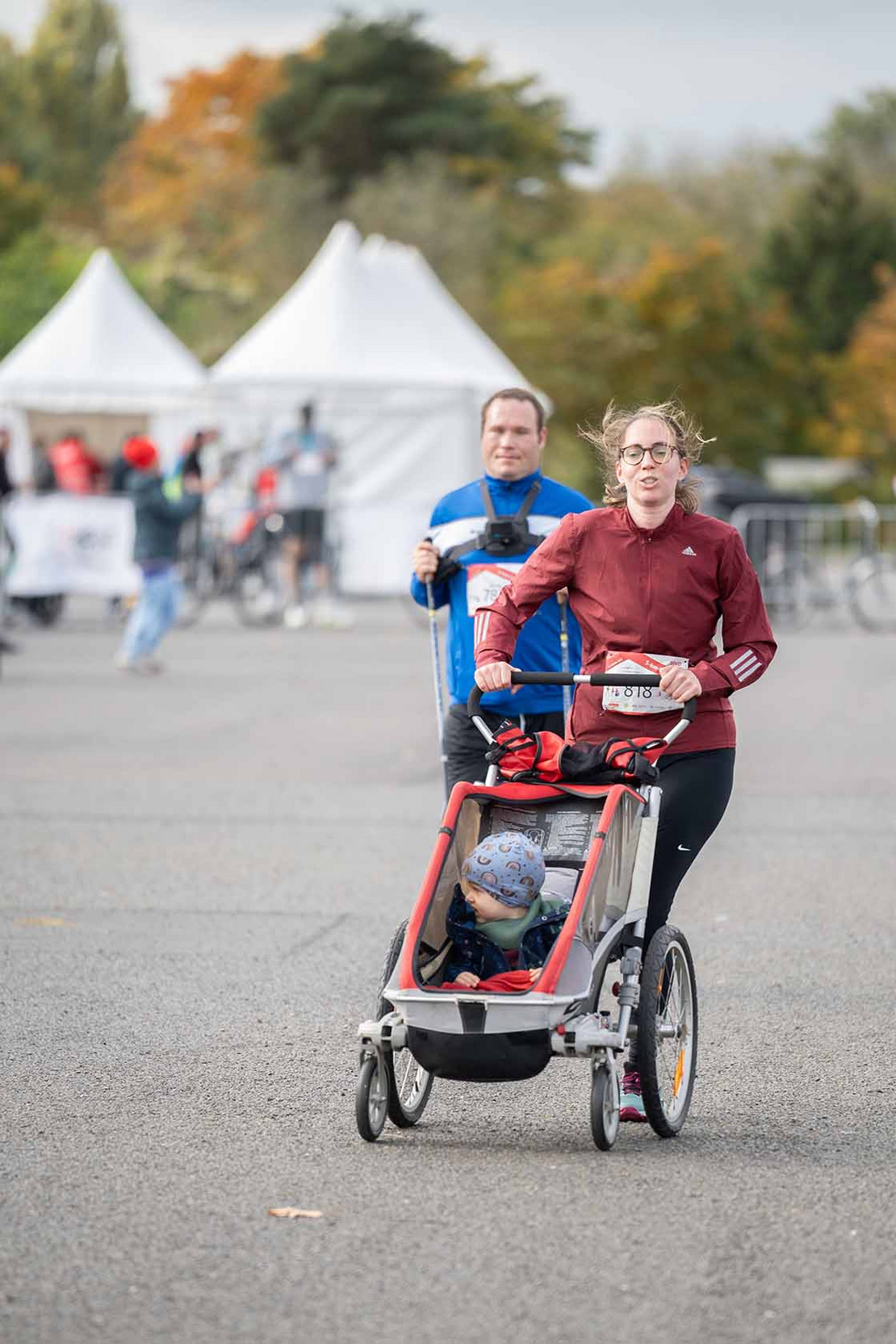 Mutter schiebt einen Kinderwagen während sie rennt. 