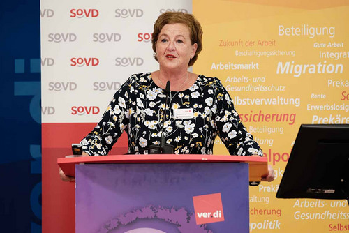 Frau spricht am Rednerpult in ein Mikrofon. 