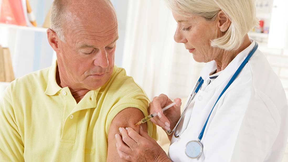 Älterer Mann bekommt von einer Ärztin eine Impfung in den Arm. 
